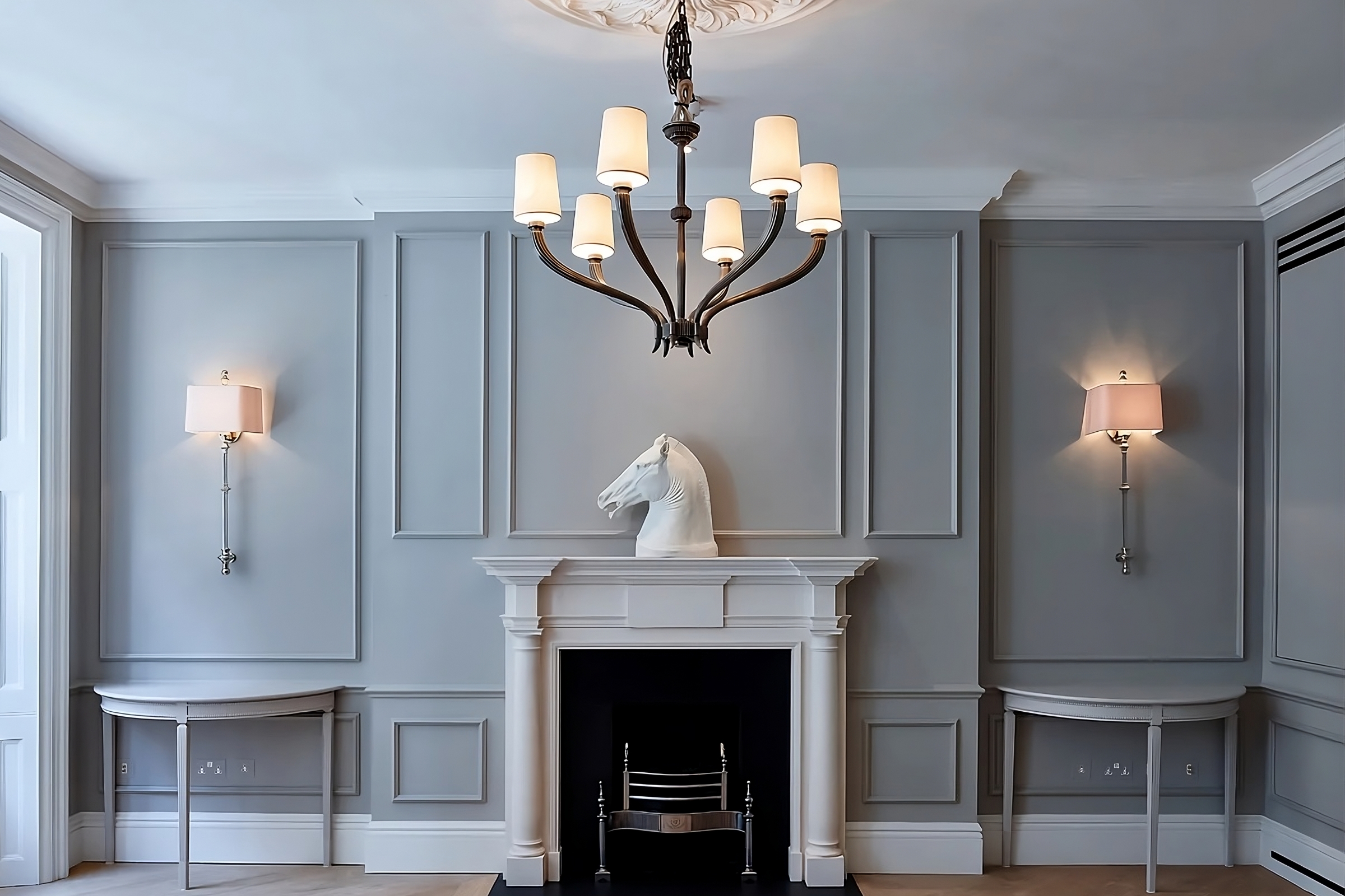 Georgian-style living room with bespoke grey wall panelling, ornate chandelier, and a sculptural horse bust on the mantel.