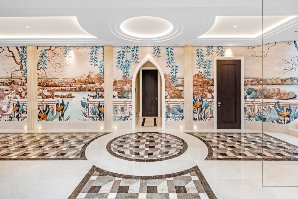 Grand entrance hall with hand-painted mural, geometric marble flooring, and architectural ceiling detailing.