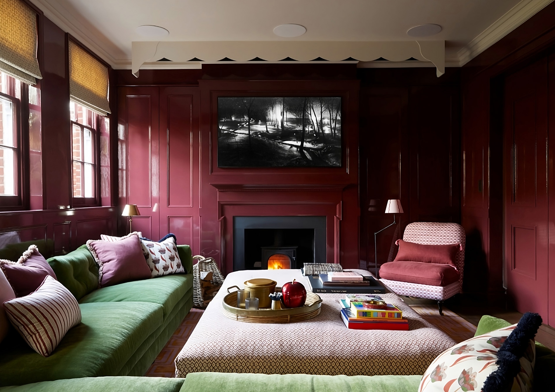 Luxurious living room with high-gloss burgundy walls, green velvet sofas, and a contemporary fireplace.
