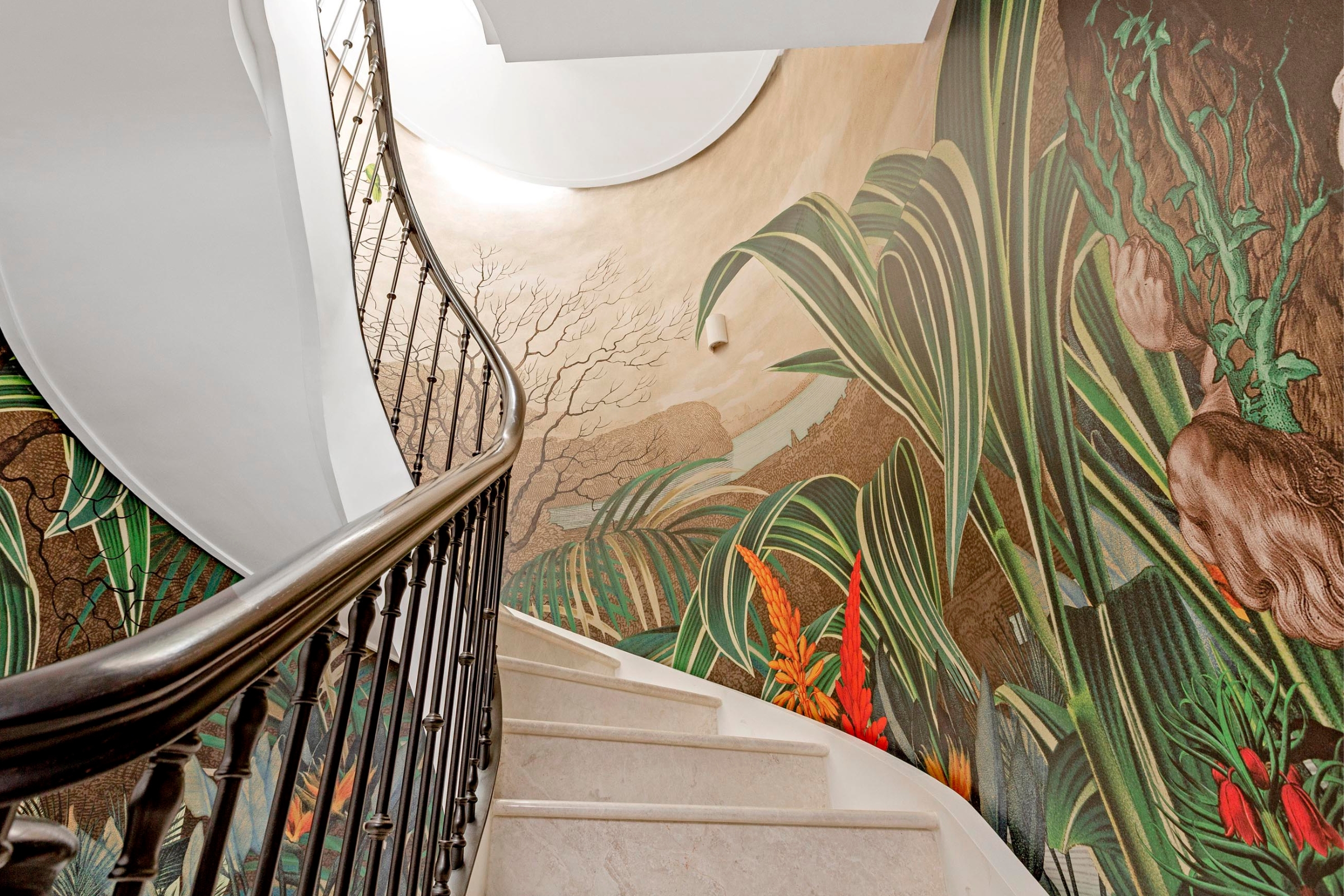 Curved staircase with detailed tropical mural spanning the stairwell wall, showcasing brushwork and bold colours.