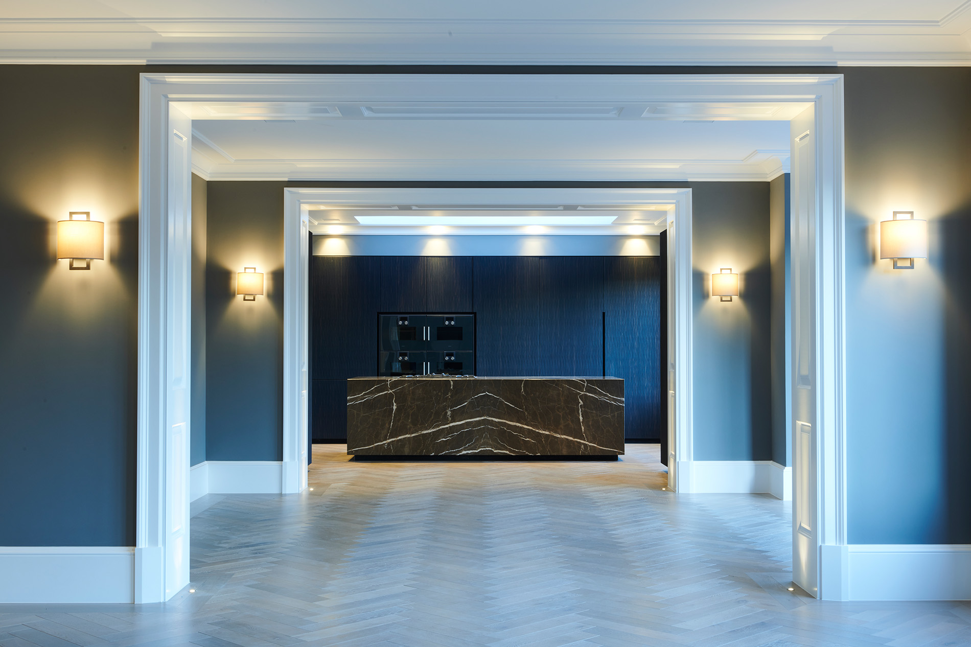 Elegant hallway with symmetrical lighting, blue-grey walls, and a feature bench at the far end.