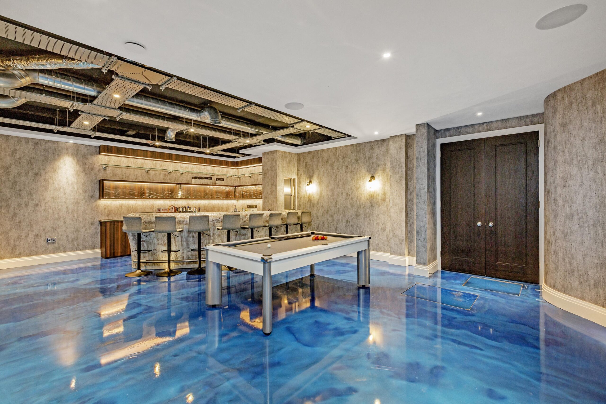 Entertainment room with high-gloss blue flooring, bespoke joinery, and warm ambient lighting highlighting bold finishes.