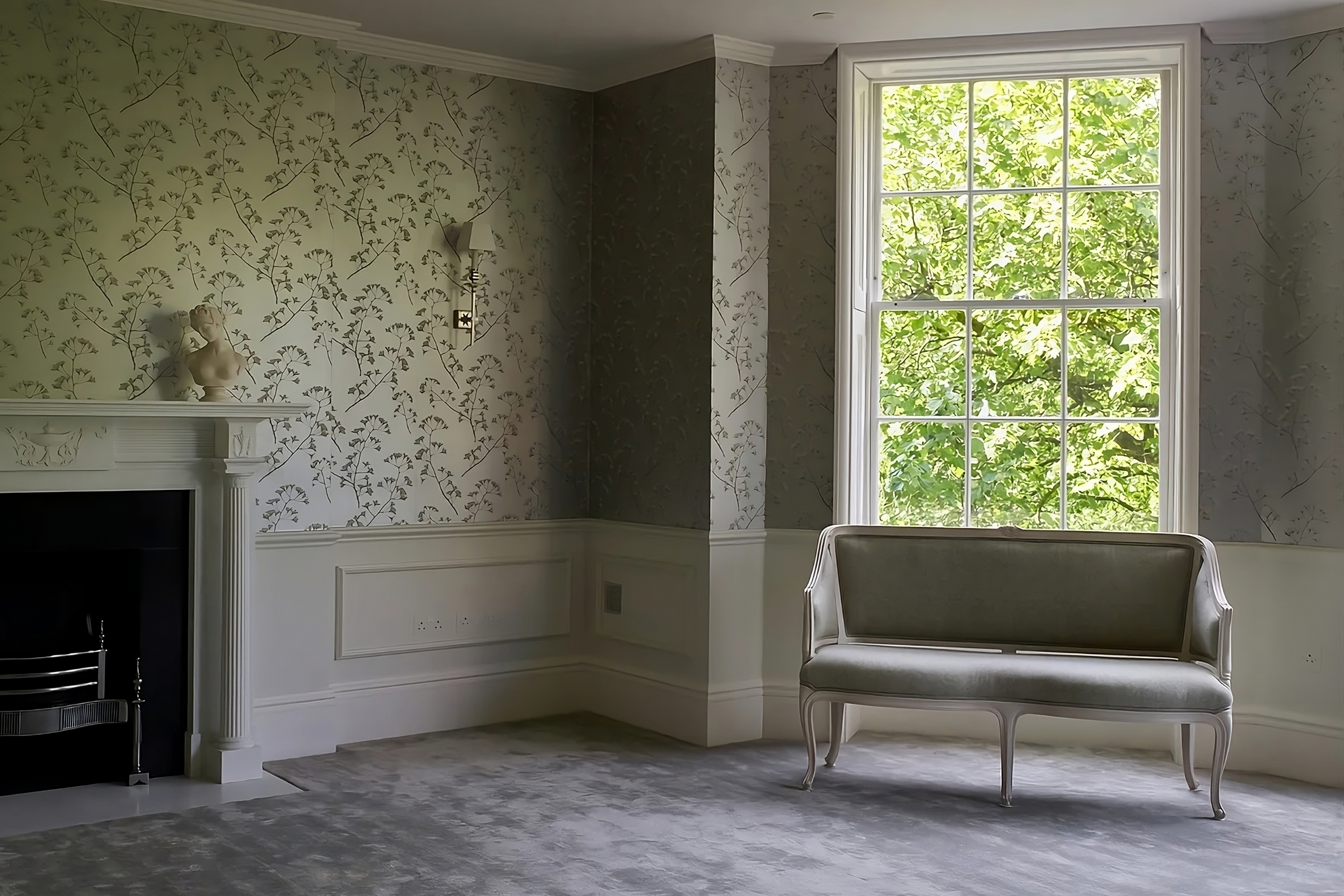 Refined Georgian sitting room with botanical silk wallcovering, bespoke joinery, and soft neutral tones framing a tall window.